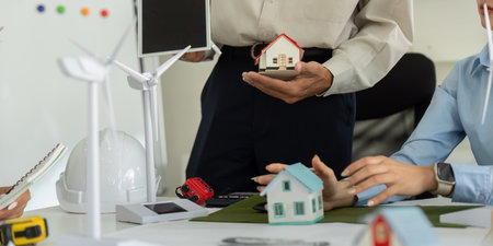 Innovative Eco Design and Team Development. Professionals evaluating renewable energy housing models during a strategic planning meeting for sustainable projects.の写真素材