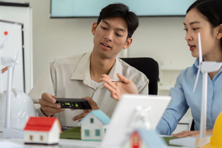 Collaboration in Sustainable Design. Young professionals engaging with digital tools to explore eco-friendly building solutions.の写真素材
