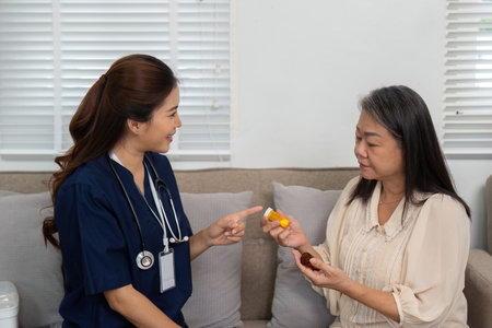 Nursing and Elderly Interaction. A caregiver assists an elderly woman with her medication in a nurturing home environment.の写真素材