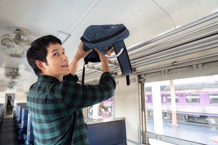 Travel and Preparation. A young man placing his backpack in the overhead compartment as he embarks...