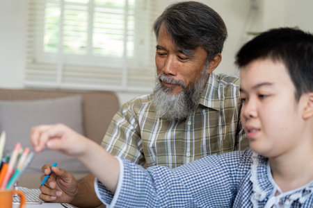 Art and Connection. A teenage girl with Down syndrome focuses on her drawing while her grandfather supports her creative process.の写真素材