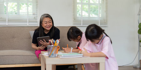 Learning and Family Support. A grandmother assists her grandchildren with their homework at home.の写真素材