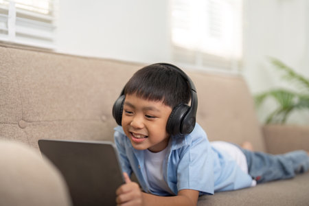 Son Enjoying Learning with Technology. A young boy happily engages with his tablet, showcasing...
