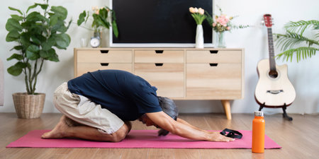 Wellness techniques for elderly man practicing yoga at homeの写真素材