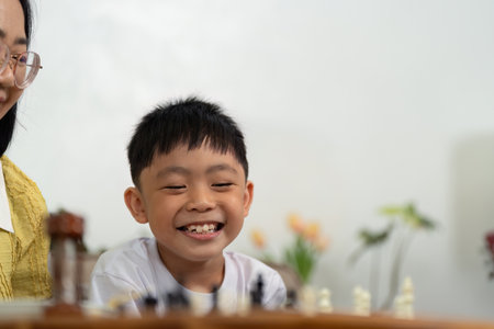 Activity mother and son smiling during chess gameの写真素材