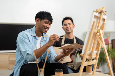 Gay couple bonding over painting and music during leisure timeの写真素材