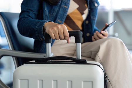Journey anticipation with traveler holding luggage and smartphone at airportの写真素材