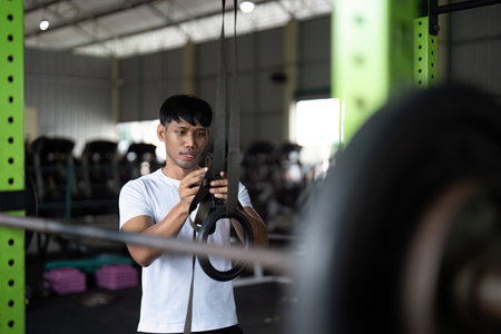 Wellness through Fitness. Young man preparing for workout on gym rings.