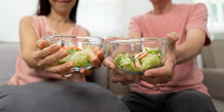 Wellness and Connection. Elderly couple enjoying healthy salads together at home.の写真素材