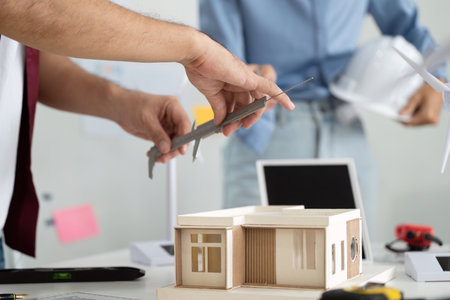 Engineer and Sustainability. Hands measuring dimensions of eco-friendly building model.
