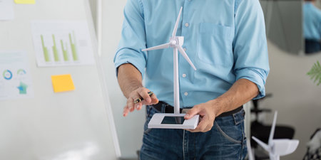 Sustainability in Action. Professional presenting wind turbine model for eco-friendly solutions.