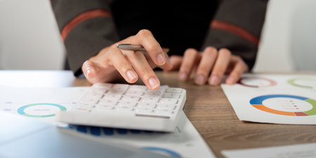 Close-Up of Business Professional Using Calculator and Analyzing Financial Data.