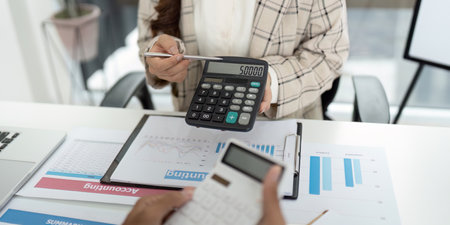 Financial Reporting. Accountant showing calculator display with figures during client meeting.
