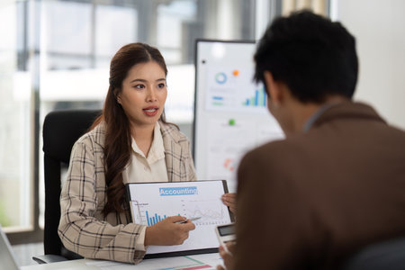 Accounting Insights and Data Presentation. Businesswoman explaining financial charts to her colleague.の写真素材