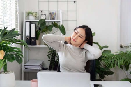 Workplace Wellness. Young woman stretching and relieving tension in a modern office.の写真素材