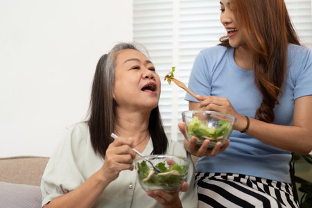 Wellness and Nutrition. Mother and daughter enjoying healthy salad together at home.の写真素材
