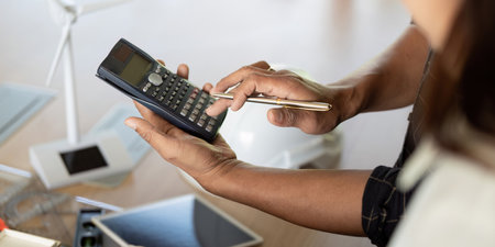 Sustainability and Engineering. Engineer using calculator for sustainable project analysis.