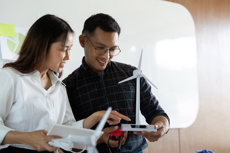 Sustainability and Engineering. Engineers collaborating on wind energy models in a modern office.の写真素材