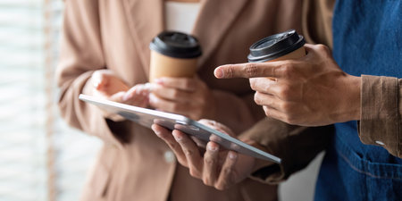 Collaboration and Coffee. Young professionals reviewing a project on a tablet while enjoying coffee.の写真素材