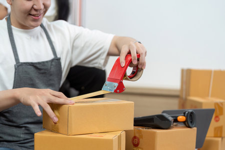 Couple packaging orders with tape and teamwork.