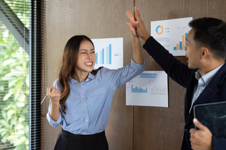 Dynamic Team Interaction. Colleagues celebrating success with high-fives in an office.