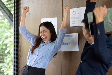 Celebrating Success in the Workplace. Colleagues expressing joy after achieving a project milestone.の写真素材