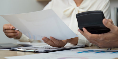 Financial Report Review. Business professional analyzing documents and using a calculator.の写真素材