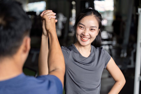 Friends engaging in friendly arm wrestling at gymの写真素材
