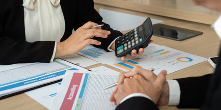 Data Analysis and Financial Planning. Professionals using calculator and reports in discussion.