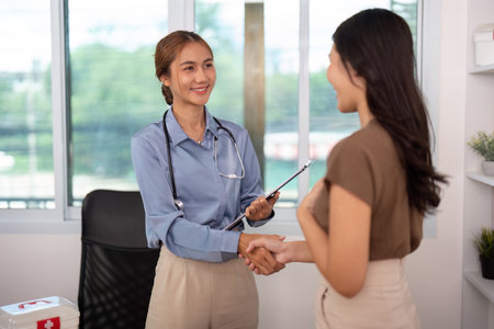 Positive Healthcare Encounter. Nurse and patient sharing a handshake in a consultation.の写真素材