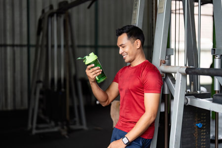 Fitness Hydration. Young man enjoying a sports drink in gym.