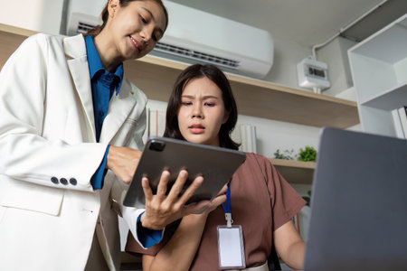 Exploring Technology in the Office. Businesswomen reviewing digital tools in a modern workspace.の写真素材
