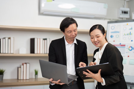 Team Collaboration and Engagement. Business professionals sharing insights with a laptop in a modern workspace.の写真素材