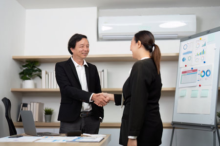 Professional Networking and Agreement. Business partners shaking hands in a modern office setting.の写真素材