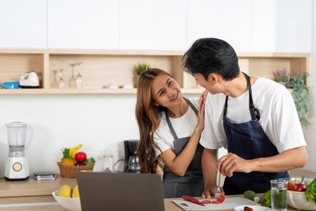 Couple Bonding While Cooking. A playful moment as a woman embraces her partner while he prepares food.の写真素材