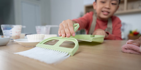 Cleaning and Responsibility. A child using a dustpan while cleaning the kitchen.