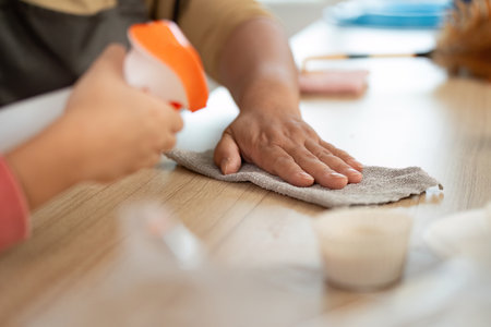 Cleaning and Family Bonding. A child helping with cleaning tasks in the kitchen.の写真素材
