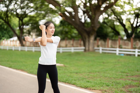 Dynamic Stretching. Young woman stretching arms outdoors in park.の写真素材