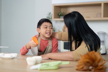 Cleaning and Family Fun. A mother and son sharing a joyful moment while cleaning.の写真素材
