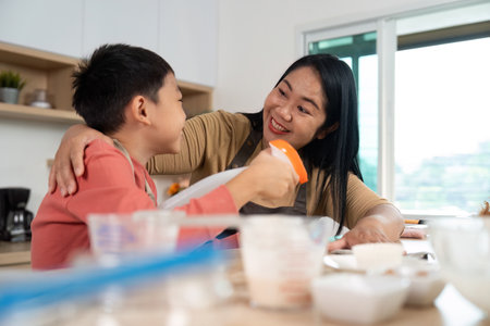 Cleaning and Baking. Mother and son sharing a delightful moment while preparing in the kitchen.の写真素材
