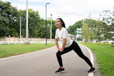 Stretching Exercises. Young woman performing lunges in park.の写真素材