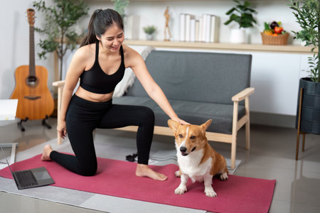Yoga and Pet Interaction. Woman enjoying yoga with her corgi in a bright living space.の写真素材