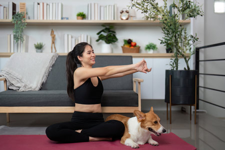 Mindful Yoga with Dog. Woman enjoying yoga poses with her corgi companion at home.の写真素材