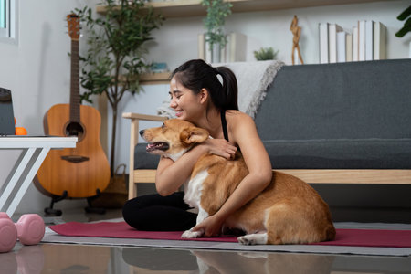 Wellness and Fitness. Young woman practicing yoga at home with her dog.の写真素材