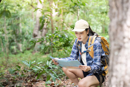 Focused Exploration. Young woman crouching to read map in forest.の写真素材