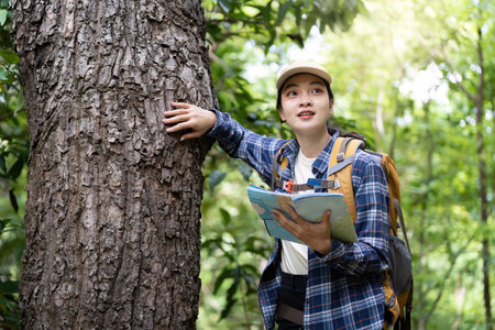 Hiking Adventure. Woman interacting with tree while holding map.の写真素材