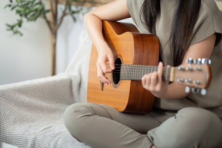 Music and Relaxation. Young woman playing acoustic guitar at home.