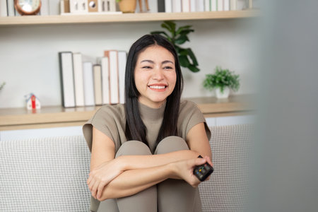 Smiling woman watching TV at home. Cozy and inviting atmosphere.の写真素材