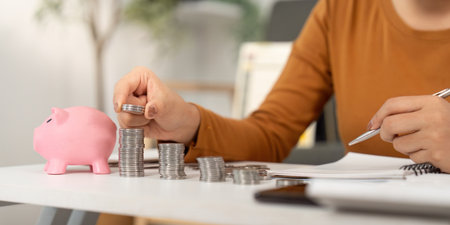 Organizing Savings. Woman stacking coins next to a piggy bank, focusing on financial planning.