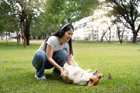 Relaxing with Corgi. Woman enjoying playful moments with her dog in a green park.の写真素材